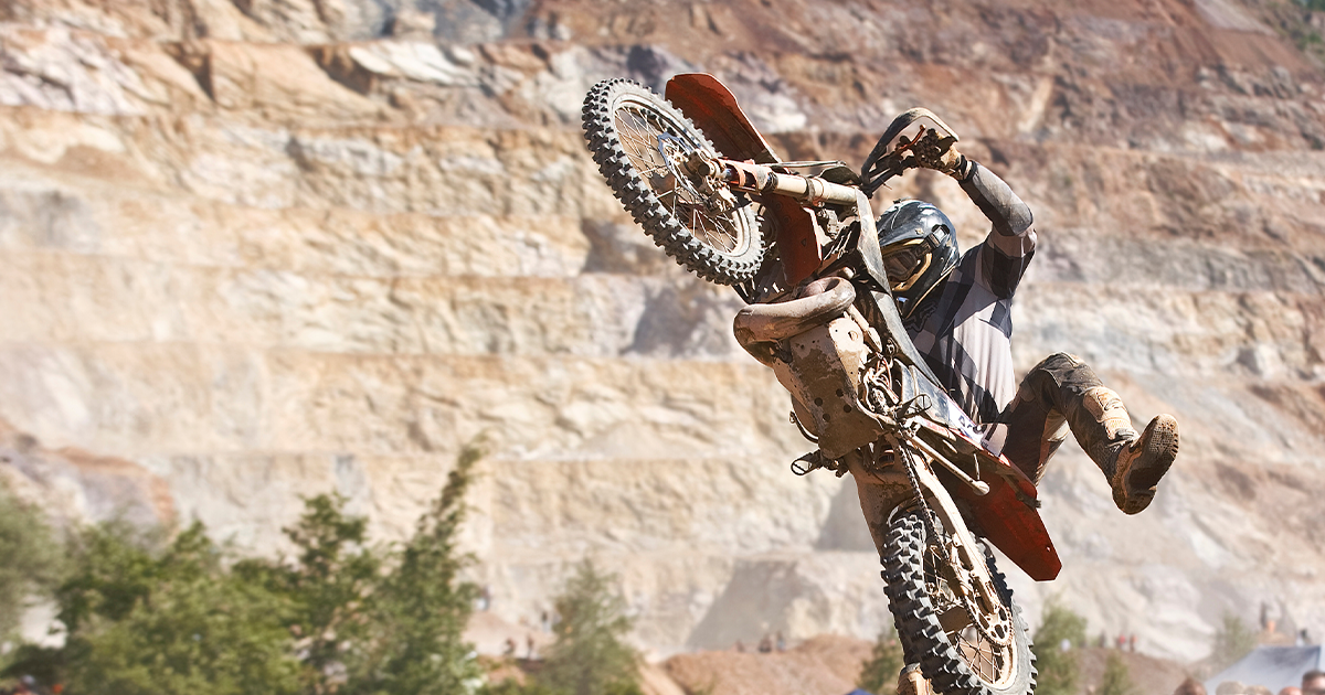 A competitor in the Erzbergrodeo rides over logs. Their bike is in a wheelie position. Conquering the World's Wildest Dirt Bike Race: The Erzbergrodeo [VIDEO]