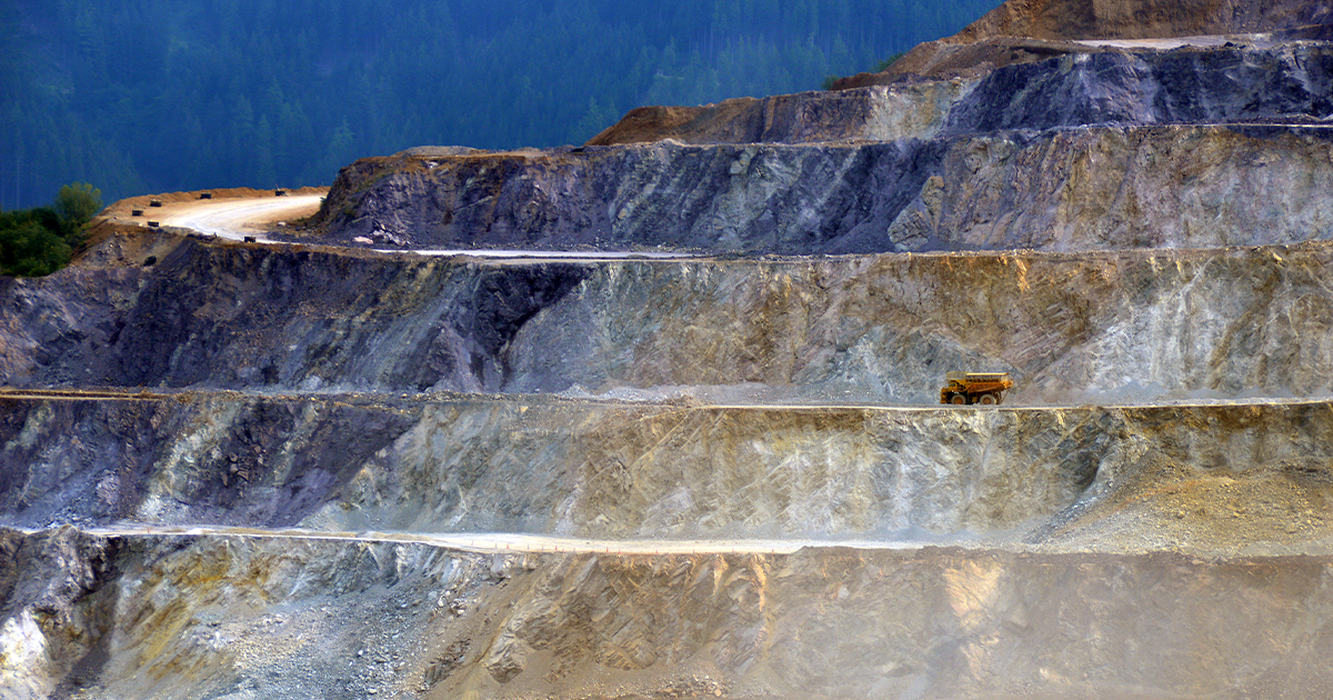 A dump truck travels across one of the giant layers of the Erzberg Mine’s mountain. It looks extremely small compared to the mountain.