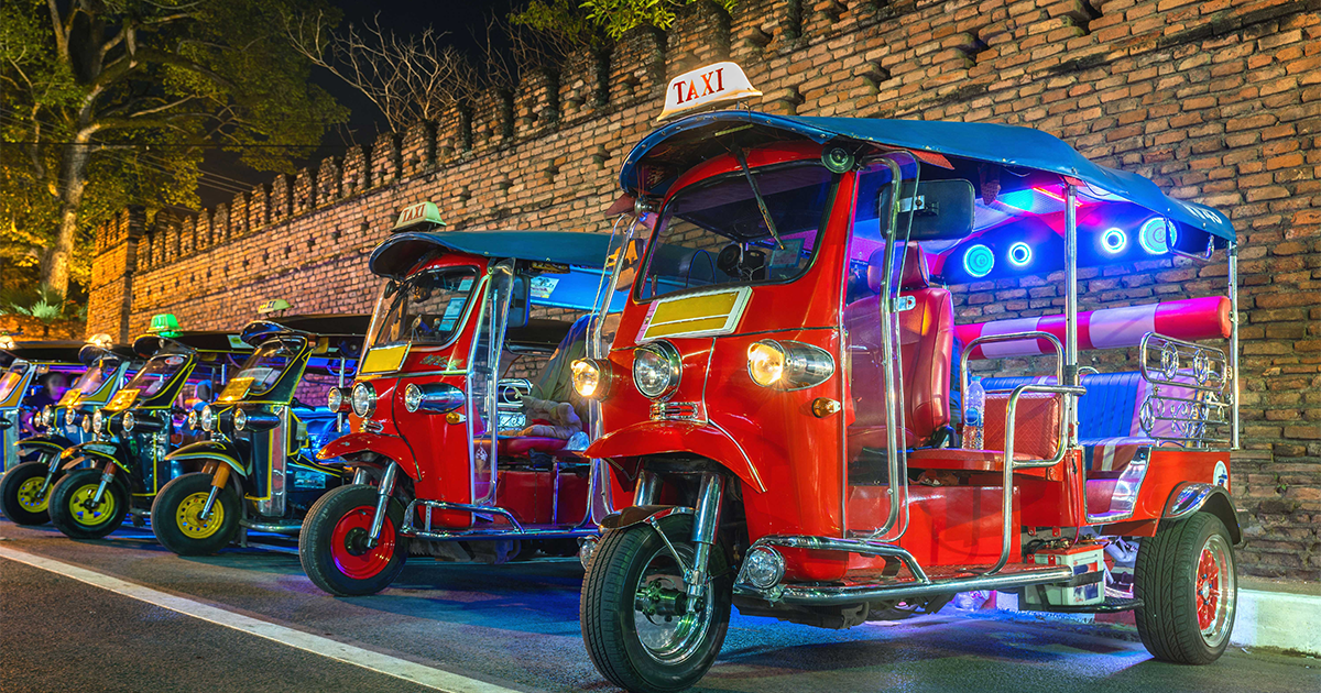 A line of brightly colored, brightly lit tuk-tuks sit in a line at night. Engineering a Wacky Auto Race: What is Tuk-Tuk Racing?